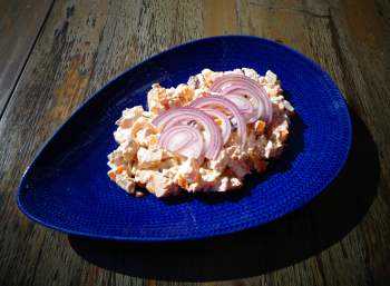 Sallad sötpotatis, recept - här upplagt på blått fat med rödlöksringar.